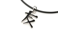 Niewielki wisiorek w kształcie chińskiego symbolu przyjaźni, wykonany z metalu nieszlachetnego w kolorze ciemnego srebra, pokryty masą jubilerską, zawieszony na kauczukowej lince z zapięciem