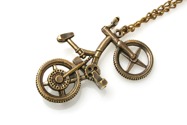 Wykonany z metalu imitującego stare złoto wisior w kształcie roweru, zawieszony na długim łańcuchu