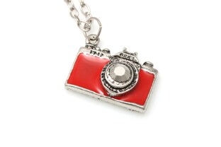 Wisiorek w stylu japan, w kształcie małego aparatu fotograficznego wykonanego z metalu nieszlachetnego, w kolorze srebra, z czerwonym laminatem, zawieszony na długim łańcuszku